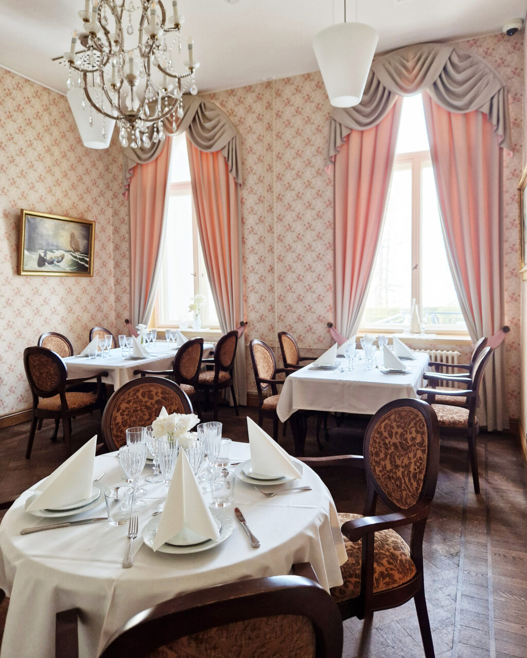 Tables and chairs in a room with pink curtains.